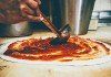 The famous sauce being applied to a Pepe's pizza. Photo by Tom McGovern Photography.