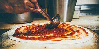 The famous sauce being applied to a Pepe's pizza. Photo by Tom McGovern Photography.
