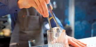 ice equipment machine maintenance bartender adding ice cube into glass at bar